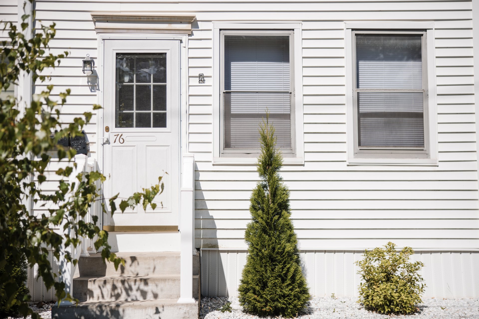 Exterior image of a white home with green shrubs in front