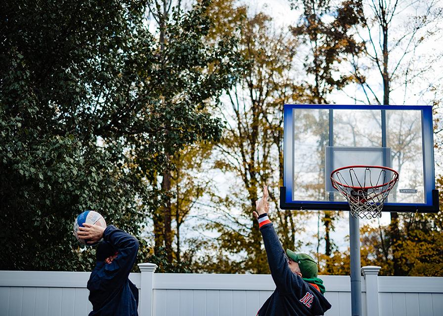 two men playing basketball outside their community residence