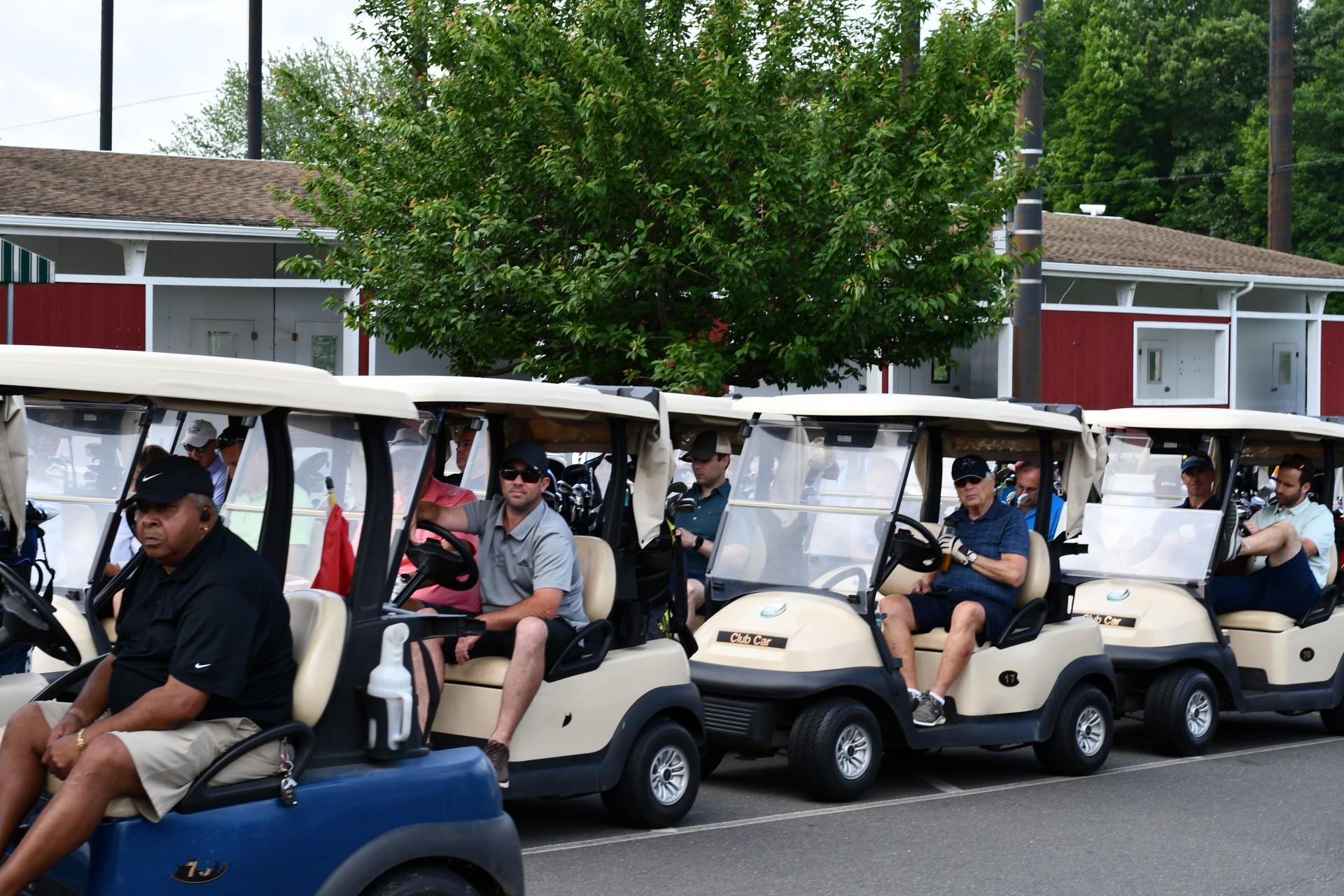 Tournament participants in a line of golf carts