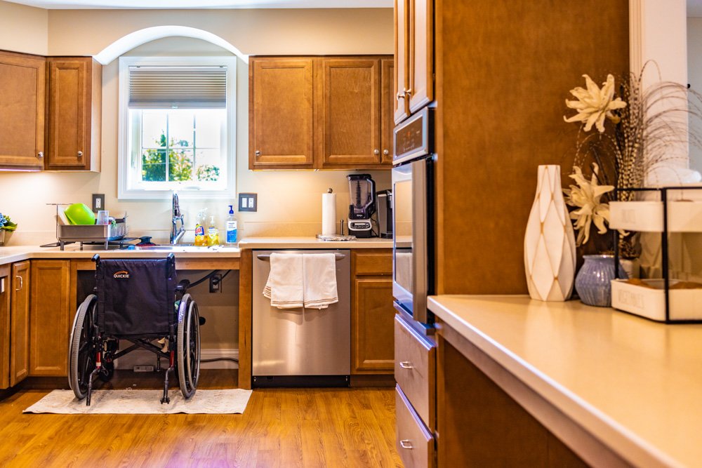 Photo of an accessible kitchen with a wheelchair at the sink showing it's accessibility