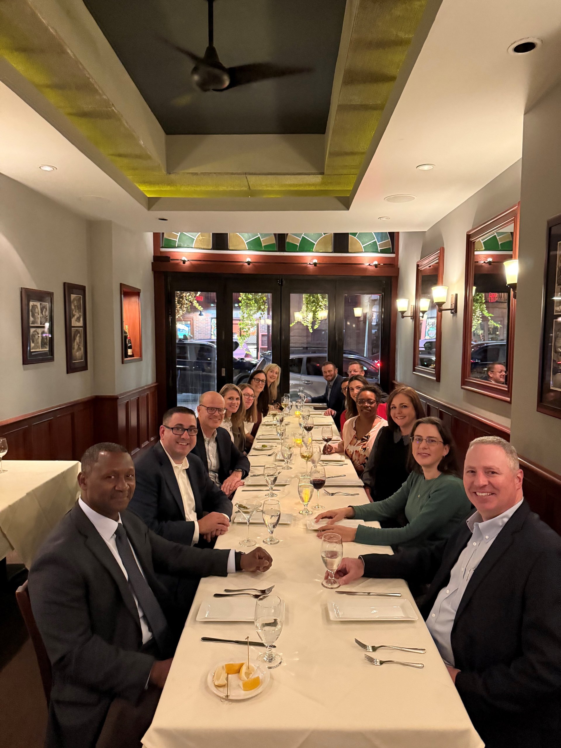 a group of individuals at a long dinner table smiling at the camera