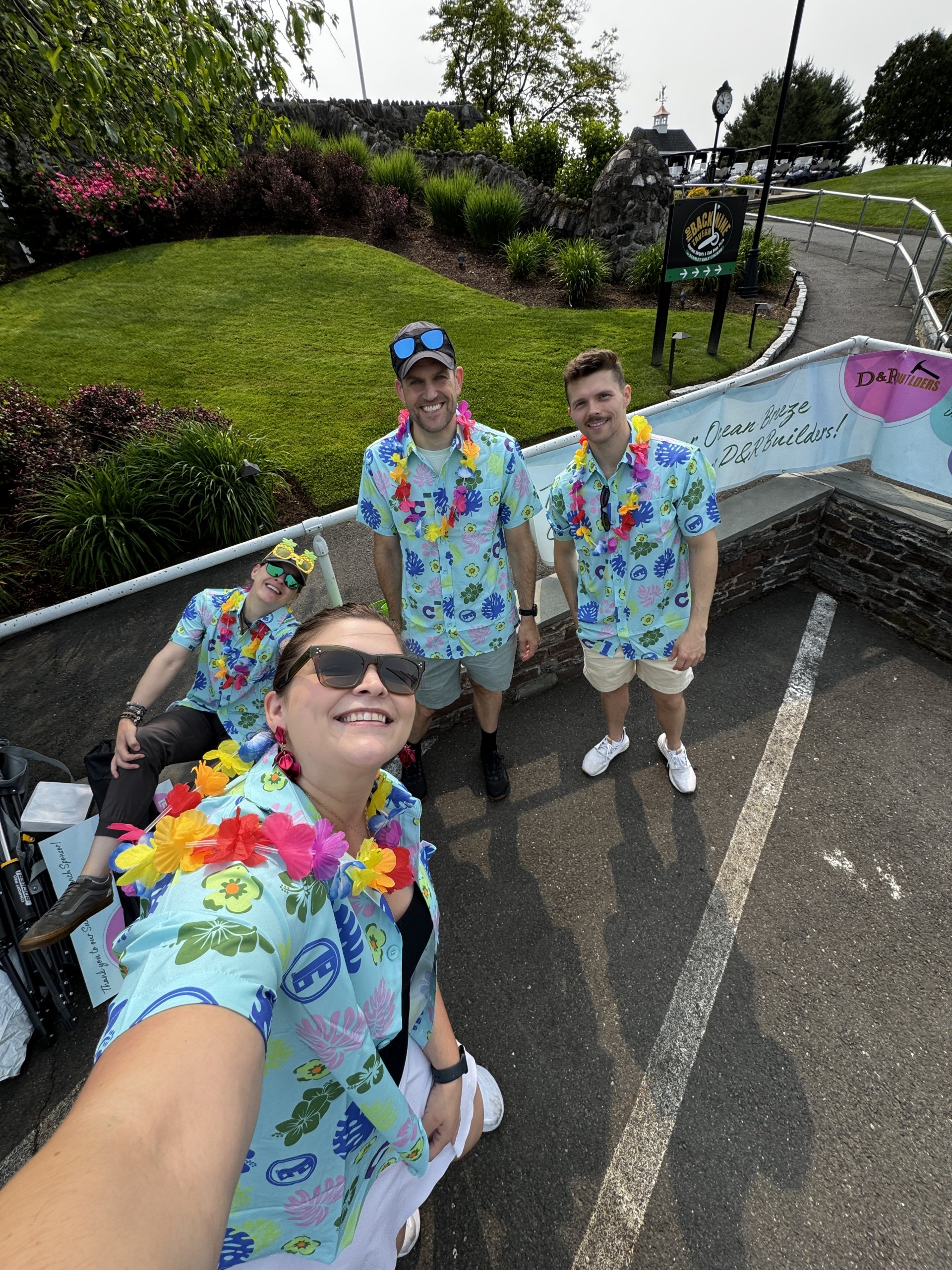 group picture of four individuals wearing fun bright tropical tshirts all wearing leis